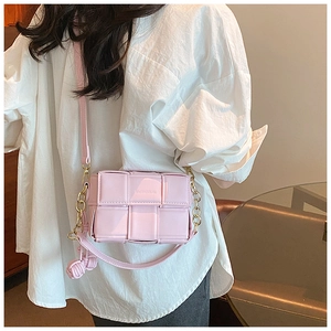 Détail du sac à bandoulière tressé rose avec texture rembourrée et chaîne dorée