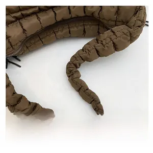 Detail of the soft quilted shoulder strap on a brown ruched cloud bag showing fabric texture