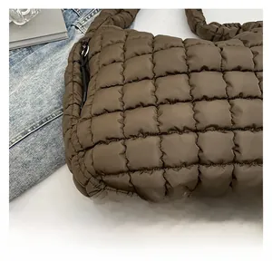 Detailed close-up of dark brown quilted puffer bag with square stitching and zip closure