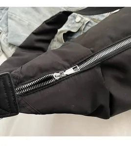 Détail de la fermeture éclair argentée sur un grand sac à bandoulière en nylon noir