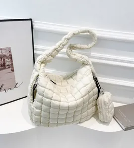 Close-up of white quilted cloud tote bag with matching mini pendant on stylish display