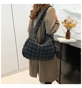 Detail of black quilted cloud bag with matching mini round zipper pouch and soft texture