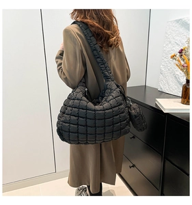 Detail of a black quilted cloud tote bag with matching coin purse and padded strap