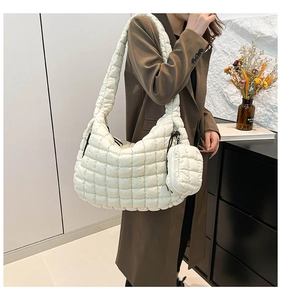 Close-up of a white quilted puffer bag with matching coin purse on a model in a long coat