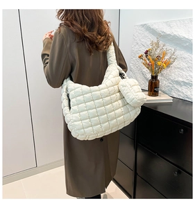 Quilted cream tote bag on shoulder of model in brown coat with matching mini pouch