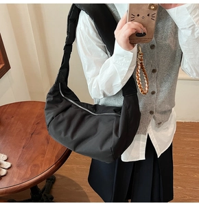 Détail du sac croissant en nylon noir avec bandoulière réglable porté par un mannequin