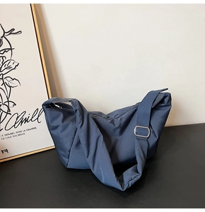 Detail of navy blue nylon dumpling bag with adjustable strap and silver metal buckle