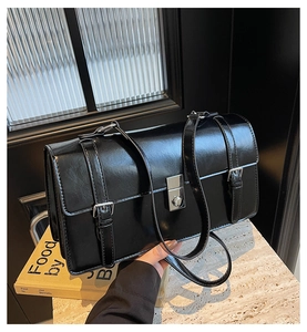 Détail du sac messager rétro en cuir ciré noir avec boucles argentées et texture polie
