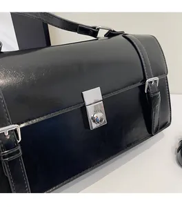Détail du sac messager rétro en cuir ciré noir avec boucle carrée argentée brillante