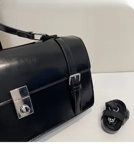 Détail de la boucle en métal argenté et de la bandoulière de ce sac à main noir vintage