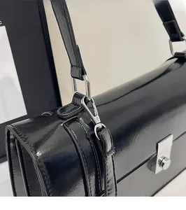 Détail de la boucle en métal argenté et de la finition en cuir verni noir brillant
