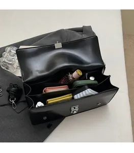 Détail des compartiments intérieurs multicouches d'un sac messager noir en similicuir