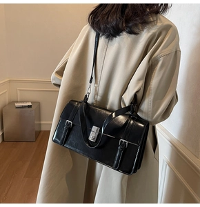 Détail d'un sac serviette noir avec fermoir argenté et structure latérale à soufflet