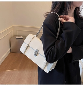Vue détaillée d'un sac à bandoulière blanc avec fermoir rotatif argenté et lanières cuir