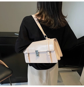 Détail du sac à main en cuir verni rose avec fermoir rotatif argenté et côtés en accordéon