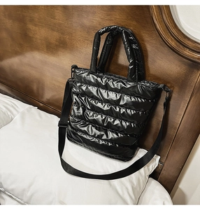 Detail of glossy quilted fabric on black shoulder bag featuring adjustable nylon straps