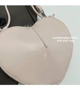 Close-up of heart-shaped crossbody bag with smooth PU leather and silver metal hooks