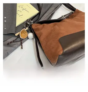 Detail of vintage brown suede patchwork tote bag with baseball themed charm pendant