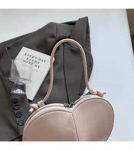 Detail of light pink heart-shaped handbag featuring smooth leather and sturdy handle
