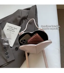 Detail showing internal capacity of the heart-shaped bag with phone and wallet inside