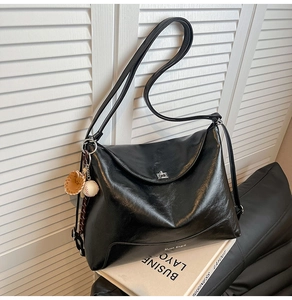 Close-up of black tote bag with silver swivel lock and baseball glove charm detail