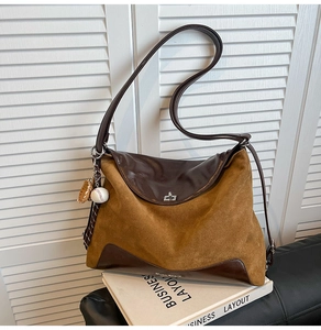 Detail of suede tote bag with leather patchwork, metal buckle, and baseball charm