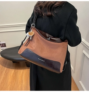 Detail view of large commuter tote bag with brown suede and leather stitching worn by model