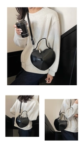 Macro view of a 3D heart-shaped crossbody bag with glossy black leather and top handle