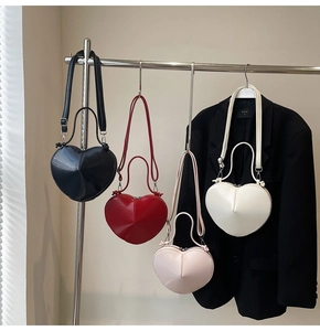 Detail view of heart-shaped crossbody bags in red, black, white, and pink finishes