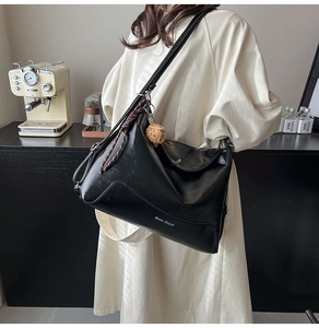 Close-up of black leather tote bag with Muon Shark logo and cute owl charm detail