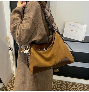 Detailed shot of a large brown suede patchwork tote bag with stylish baseball charm accessory