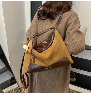 Large suede tote bag with leather straps and a baseball charm shown on a model