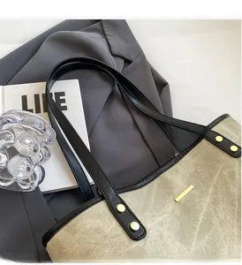 Dettaglio borsa tote in tela con manici in pelle e borchie dorate su abito elegante