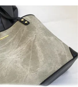 Dettaglio del tessuto grigio con finiture in pelle nera e rivetti dorati sulla borsa tote