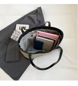 Vista dall'alto di un'ampia borsa tote kaki con tablet, taccuino e ombrello all'interno