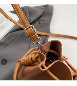 Macro detail of brown pebbled leather texture and silver metal hardware on a bucket bag