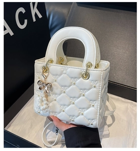 Détail du mini sac matelassé blanc avec ferrures dorées et breloque nœud en perles