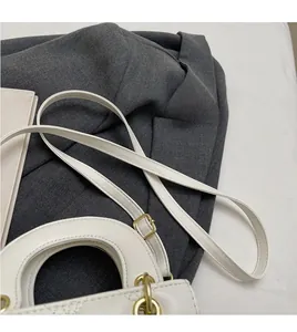 Détail de la texture en cuir blanc matelassé et ferrures dorées sur un petit sac à main
