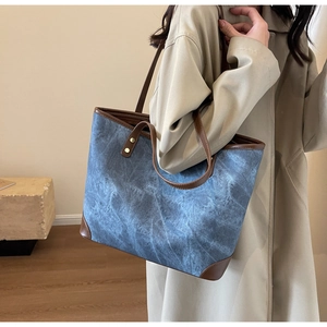 Dettaglio della borsa tote in denim blu con finiture in pelle marrone su modella