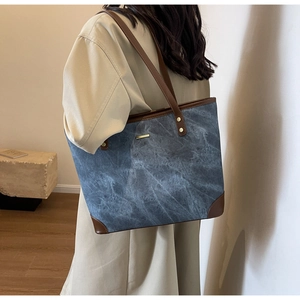 Dettaglio della borsa tote con motivo marmo blu e finiture in pelle marrone su modella