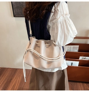 Close-up of beige bucket bag featuring pebbled leather texture and drawstring closure