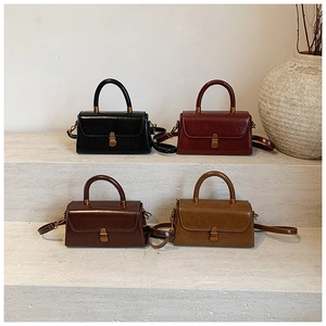 Close-up of vintage leather handbags in black, dark red, and brown on a stone pedestal