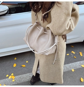 Detail of apricot pleated bucket bag with lychee grain texture and knotted strap