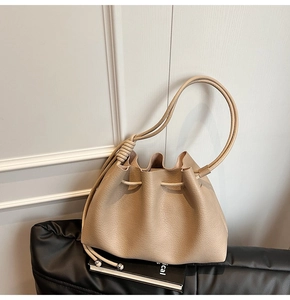 Close-up of beige drawstring bucket bag featuring lychee grain leather texture and knotted strap