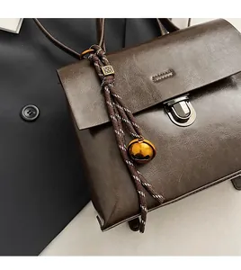 Detailansicht der braunen Ledertasche mit geflochtenem Anhänger und goldenem Drehverschluss