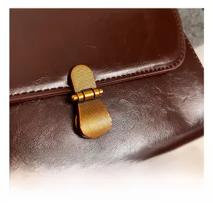 Close-up of vintage brown leather bag featuring lychee texture and bronze metal lock