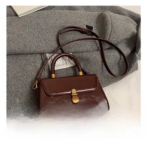 Close-up of small dark brown leather square bag with vintage gold clasp on grey wool