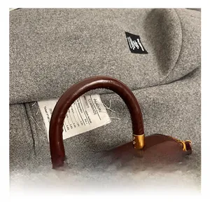 Close-up of brown polished leather handle with gold hardware on a vintage square bag