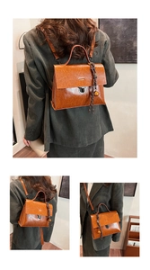 Detailaufnahme der camelfarbenen PU-Tasche mit Metallschloss und Glockenanhänger