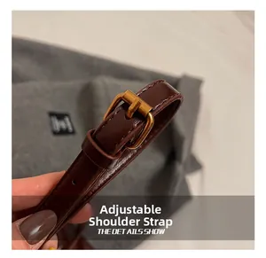 Close-up of the adjustable dark brown leather shoulder strap with a vintage gold buckle